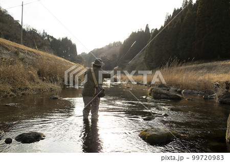 早春の里川でフライフィッシングをする男性 99720983