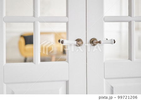 Old-style door, white - handle close up. The interior of a bright living room in a modern apartment. Old-style door, white - handle close up. The interior of a bright living room in a modern apartment. 99721206
