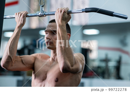 A man does a chest pulldown in the gym. 99722278
