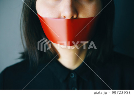 Woman with red adhesive tape over her mouth Woman with red adhesive tape over her mouth 99722953