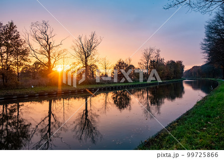 Beautiful sunset over a river with green bushes and color rich sky 99725866