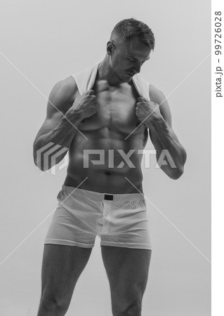 Handsome young muscular man posing shirtless over grey studio background. Masculinity and strength. Concept of men's health, beauty of male body 99726028