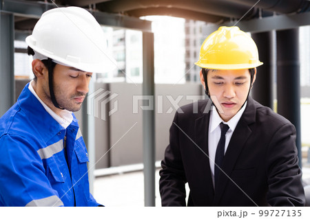 Professional Asian foreman and construction manager talking - discussing about building structure plant together. Businessman and construction engineer having a discussion. 99727135