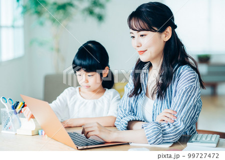 リビングで在宅ワークする母親と寄り添う娘。 リビングで在宅ワークする母親と寄り添う娘。 99727472