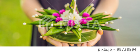 BANNER, LONG FORMAT A female tourist holds the Loy Krathong in her hands and is about to launch it into the water. Loy Krathong festival, People buy flowers and candle to light and float on water to BANNER, LONG FORMAT A female tourist holds the Loy Krathong in her hands and is about to launch it into the water. Loy Krathong festival, People buy flowers and candle to light and float on water to 99728894