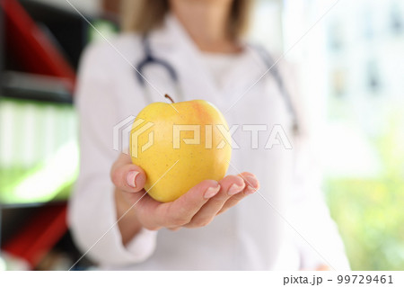 Doctor nutritionist holding ripe yellow apple in hand 99729461