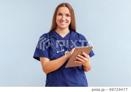 Smiling young woman doctor work on tablet on blue background Smiling young woman doctor work on tablet on blue background 99729477