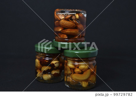 Glass jars with nuts in honey. Delicious sweets. Nuts in honey. Sweet nuts. 99729782