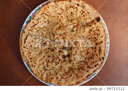 Potato stuffed paratha, aloo vali roti, torn in the middle for the filling visibility, top view. A round oriental flatbread stuffed with potato, onion, herbs, spices, popular in the Punjab. Close-up. Potato stuffed paratha, aloo vali roti, torn in the middle for the filling visibility, top view. A round oriental flatbread stuffed with potato, onion, herbs, spices, popular in the Punjab. Close-up. 99731212