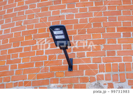 Lantern on the background of the old brick wall. A lamp on an ancient brick. Street lighting. Modern LED light 99731983