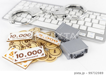 オモチャのお金とアタッシュケースと手錠とキーボード。マネーロンダリングのイメージ 99732089