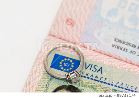 An engagement ring on a European visa stamp as a symbol of emigration or marriage 99733174
