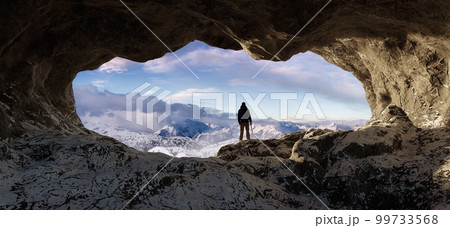 Adventurous Man Hiker standing in an Ice Cave with rocky mountains in background. Adventure Composite Adventurous Man Hiker standing in an Ice Cave with rocky mountains in background. Adventure Composite 99733568