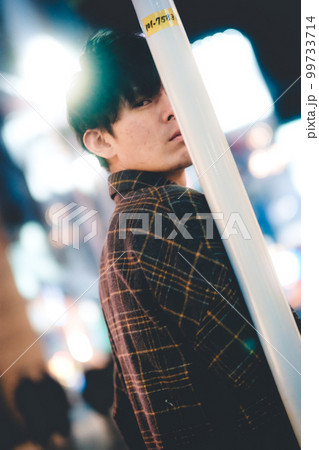 夜の街でポールに寄りかかる男性 99733714