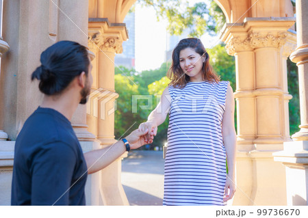 男性の手を取り階段を下りる妊婦の女性 99736670