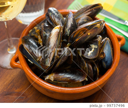 Delicious baked mussels on a bowl with onion sauce at table 99737496