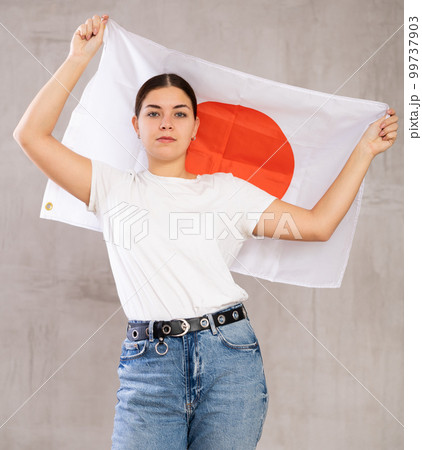 Calm girl stands with flag of Japan. Isolated on gray background Calm girl stands with flag of Japan. Isolated on gray background 99737903