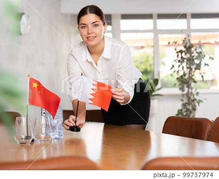 Young female attendant putting up flags for international negotiations between china and bahrain Young female attendant putting up flags for international negotiations between china and bahrain 99737974