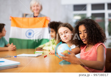 Female teacher showing indian flag to kids in geography class Female teacher showing indian flag to kids in geography class 99738017