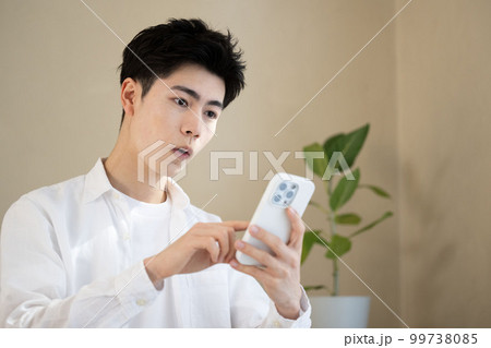スマホを持って驚く若いハンサムな男性　アップ 99738085