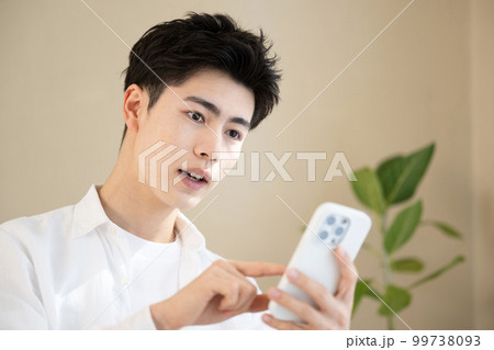 スマホを持って驚く若いハンサムな男性 アップ スマホを持って驚く若いハンサムな男性 アップ 99738093
