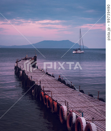 Old wooden fishing pier goes into the sea on sunset. Resort city Novyi Svet, Crimea 99739490