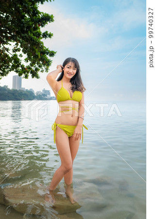 Sexy asian woman Wear a yellow body suit. Standing in the sea 99740327