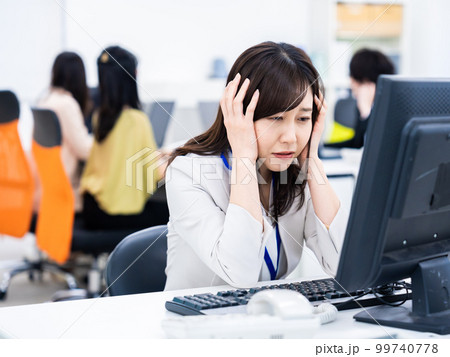 デスクワークをしながら頭を抱えるビジネスウーマン 99740778