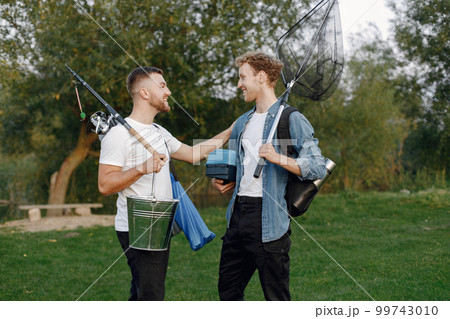 Friends is ready to fishing. Men holding a fishing equipment. One man wearing rose t-shirt and other blue shirt. 99743010