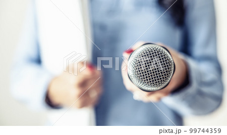 Female journalist at a press conference with a microphone and notebook 99744359