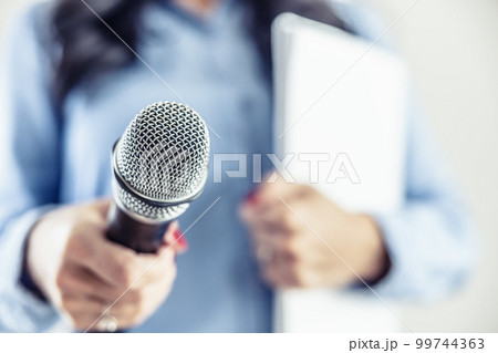 Investigative journalist with microphone in other hand notebook - Close up Investigative journalist with microphone in other hand notebook - Close up 99744363