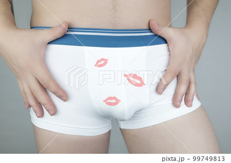 Close-up of a man in white underwear. The girl sticks to the man and stretches her hands to his shorts. Lipstick marks on underpants. A hint of intimacy and oral sex..Photo without a face 99749813