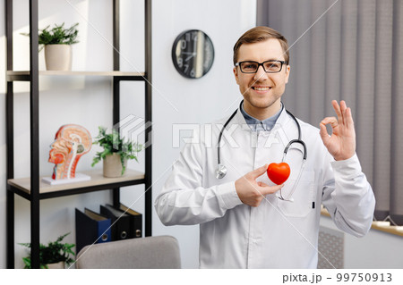 Doctor in white coat and glasses holding a red heart at hospital office. Medical health care and doctor staff service concept 99750913