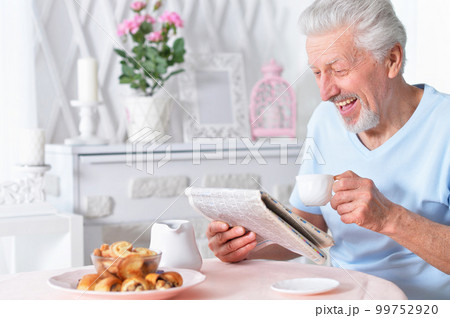 Emotional senior man reading newspaper at home 99752920