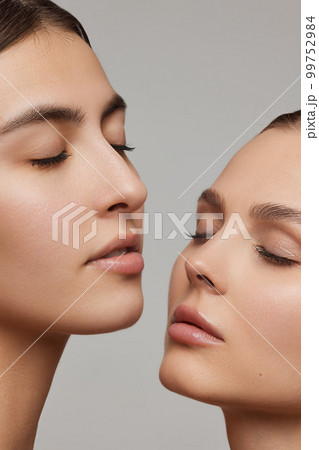 Vertical cropped portrait of young beautiful female couple. Models with well-kept skin and nude makeup. Concept of emotions, beauty, vision, health and fashion Vertical cropped portrait of young beautiful female couple. Models with well-kept skin and nude makeup. Concept of emotions, beauty, vision, health and fashion 99752984