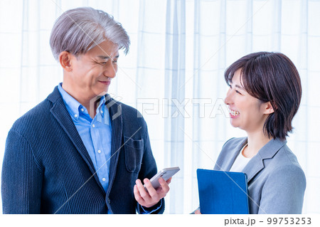 立ち話をするミドル男性の上司と若い女性の部下 99753253