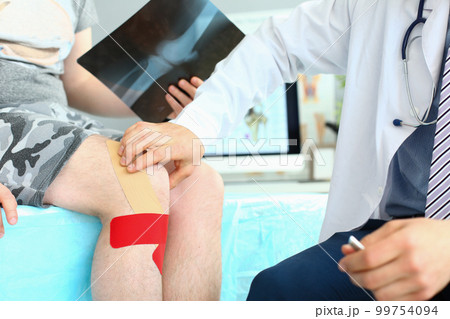 X-ray image of knee injury patient with kinesio tape on knee at orthopedist appointment 99754094