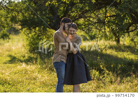 man telling his girlfriend's secret in his ear 99754170
