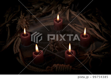 Occultist dripping hot wax on voodoo doll, magic rituals, black spell, horror. Occultist dripping hot wax on voodoo doll, magic rituals, black spell, horror. 99754385