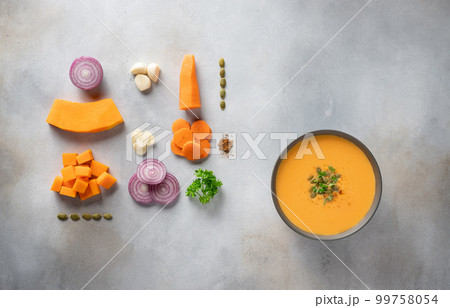 autumn pumpkin soup in dark bowl and ingredients for cooking. autumn pumpkin soup in dark bowl and ingredients for cooking. 99758054