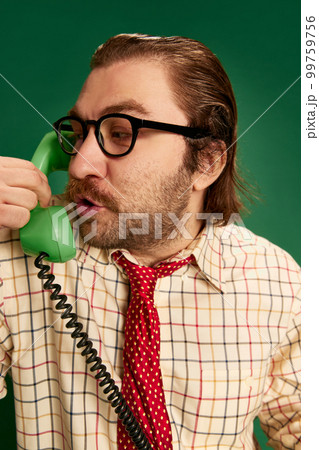 Portrait of retro mature man with moustache and beard in eyeglasses in vintage fashion clothes talking on phone over dark green background. Portrait of retro mature man with moustache and beard in eyeglasses in vintage fashion clothes talking on phone over dark green background. 99759756