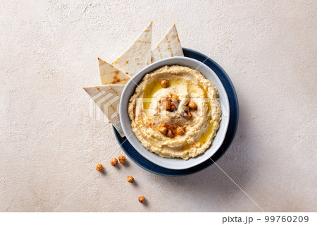 Hummus, chickpea dip in ceramic bowl over beige textured background. 99760209