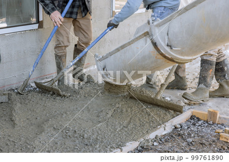 Concrete mixing truck pours concrete for paving around new house as it is being mixed 99761890