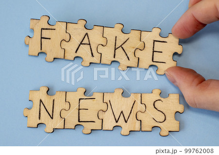 Wooden puzzles with Fake News on a dovish background in a woman's hand. Misinformation, propaganda, clickbait, media literacy. Wooden puzzles with Fake News on a dovish background in a woman's hand. Misinformation, propaganda, clickbait, media literacy. 99762008