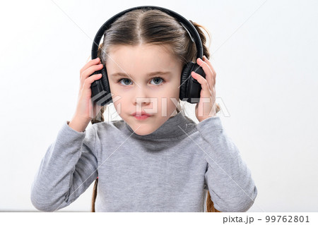 A child with headphones on a white background, a cheerful and beautiful girl with headphones. A child with headphones on a white background, a cheerful and beautiful girl with headphones. 99762801
