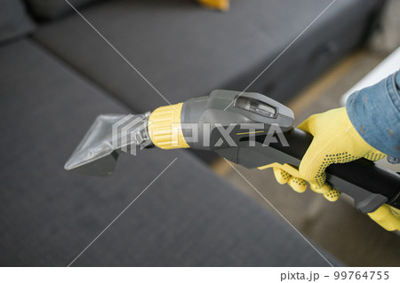 Man in protective rubber glove cleaning sofa with professionally extraction method with washing vacuum cleaner. Early spring regular cleanup. Commercial cleaning company concept 99764755