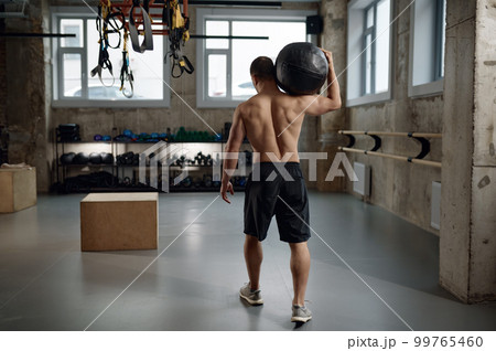 Portrait of male athlete holding med ball on shoulder after functional training 99765460