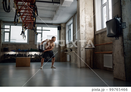 Full length portrait of young muscular man training with med ball in gym 99765466