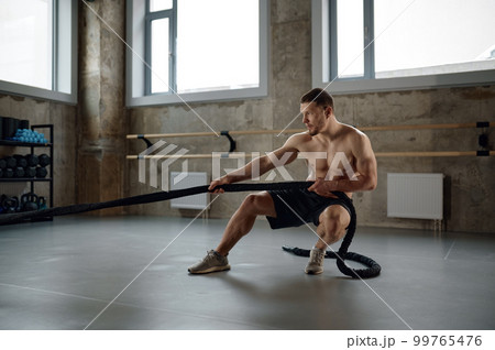 A strong man pulling training sports rope front view A strong man pulling training sports rope front view 99765476