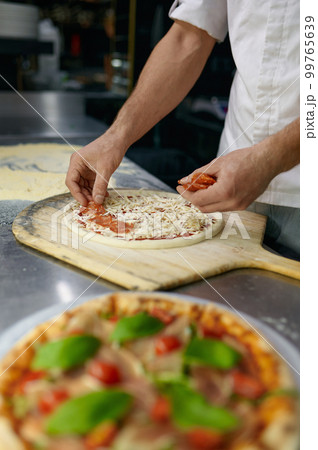 Above view on chef hand preparing pizza base on professional kitchen Above view on chef hand preparing pizza base on professional kitchen 99765639